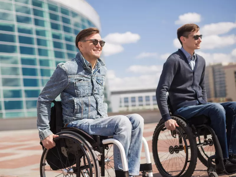 Two disabled friends outside smiling