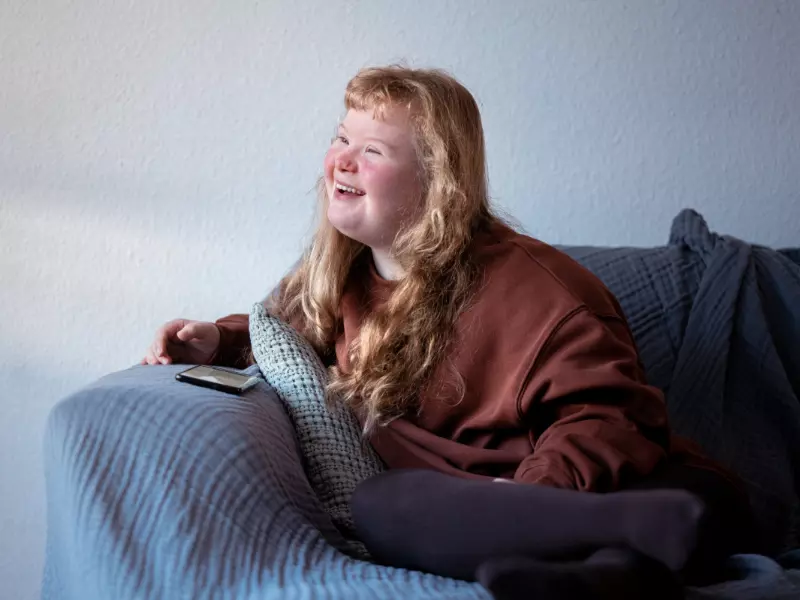 Girl with down syndrome sitting on couch and smiling