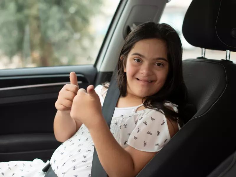 Disabled girl sitting in car giving the thumbs up