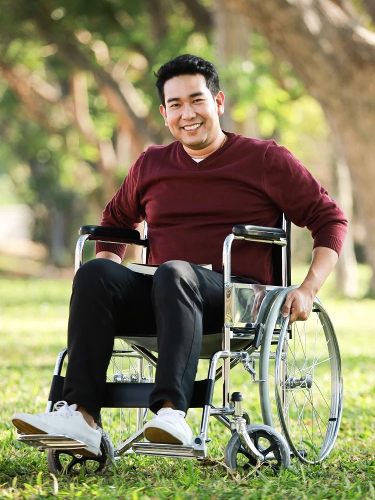 Man in wheelchair in park smiling at camera