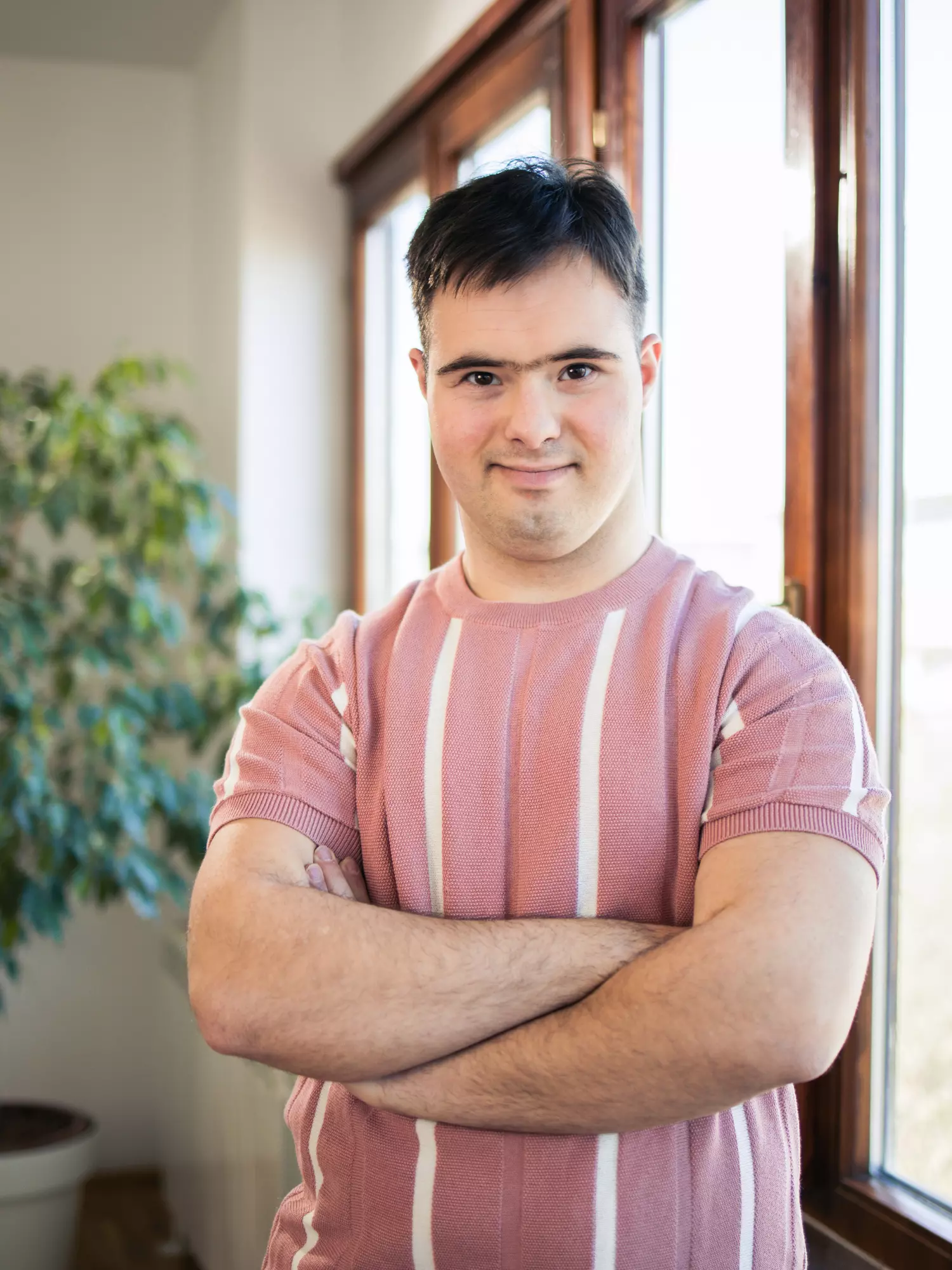 Man with down syndrome smiling at camera with arms crossed