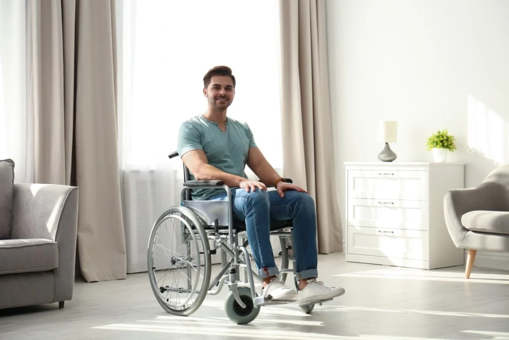 Disabled man in wheelchair in living room at home smiling at camera
